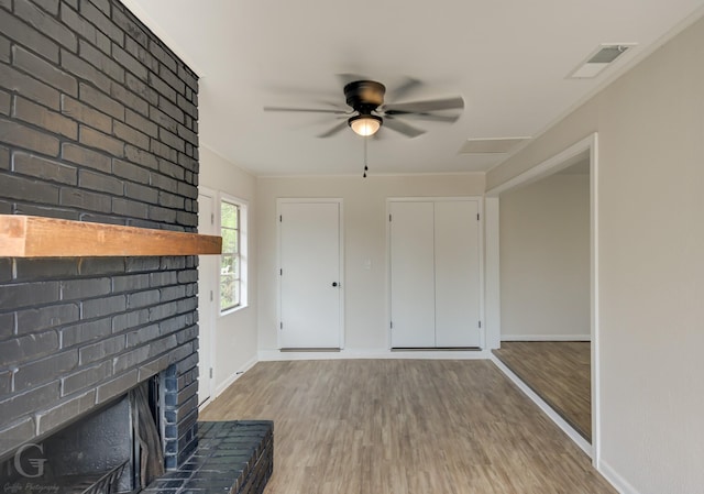unfurnished living room featuring wood finished floors, visible vents, a fireplace, and ceiling fan