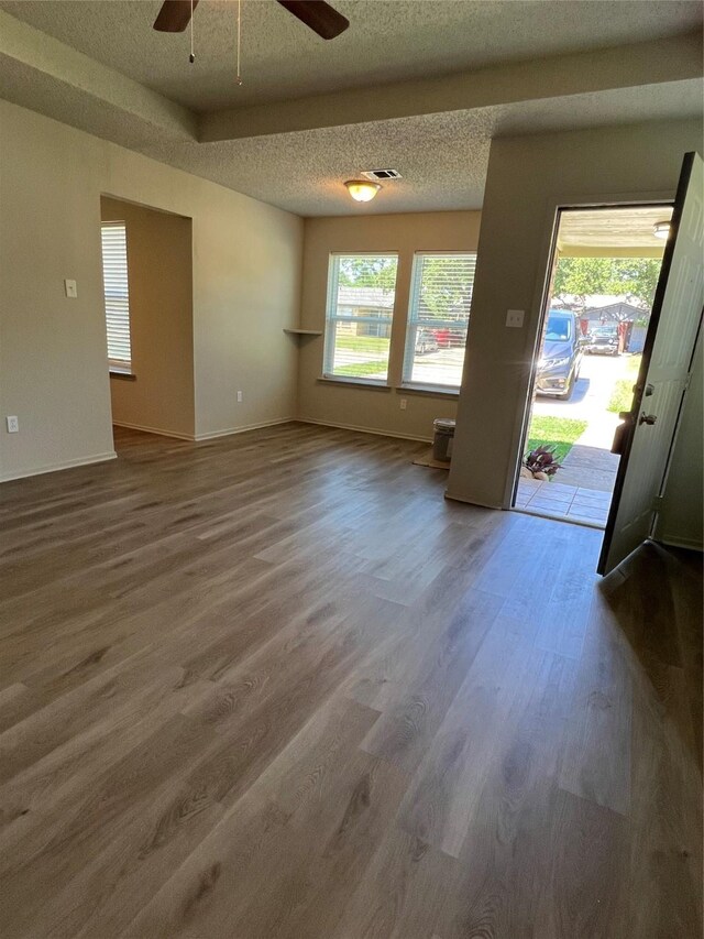 interior space featuring ceiling fan, baseboards, wood finished floors, and a textured ceiling