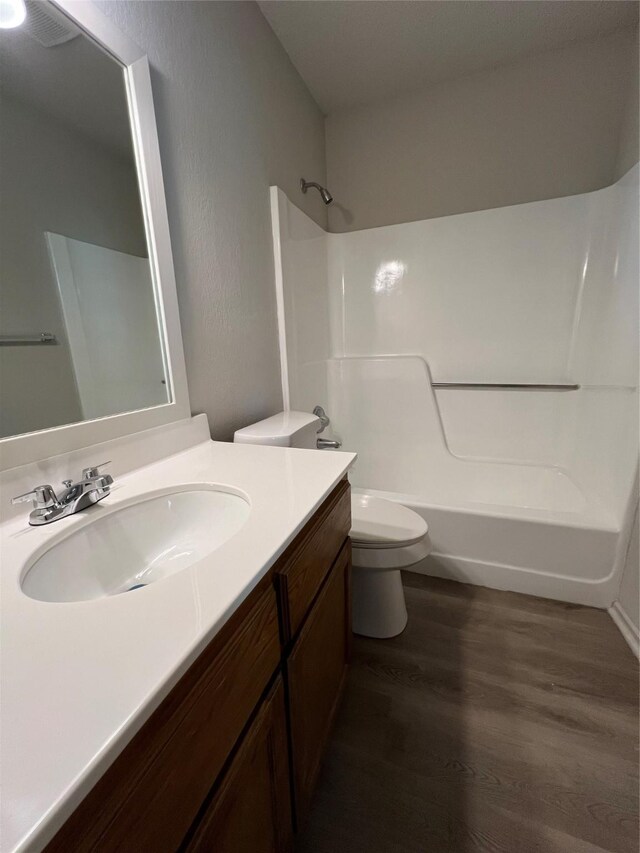 full bath featuring wood finished floors, toilet, vanity, and shower / bathtub combination