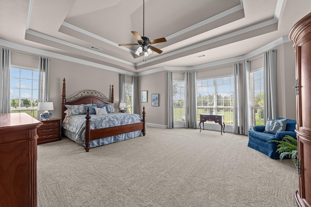 carpeted bedroom with a tray ceiling, visible vents, crown molding, and a ceiling fan
