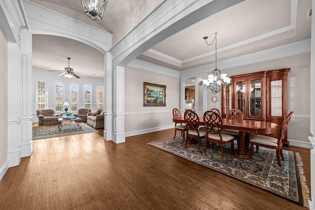 dining space with baseboards, arched walkways, wood finished floors, and ceiling fan with notable chandelier