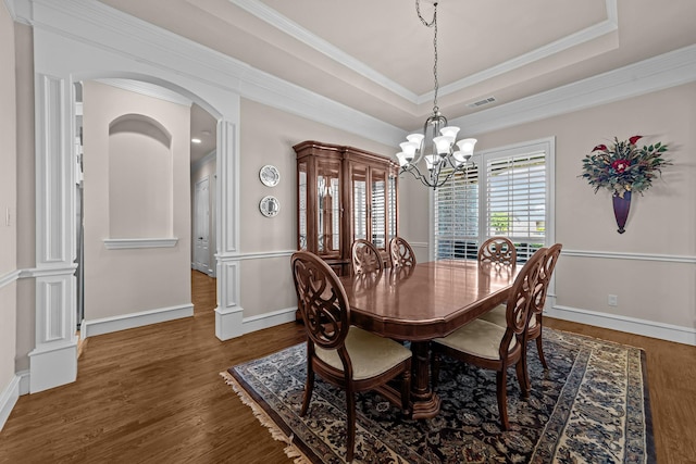 dining area with crown molding, wood finished floors, arched walkways, an inviting chandelier, and visible vents