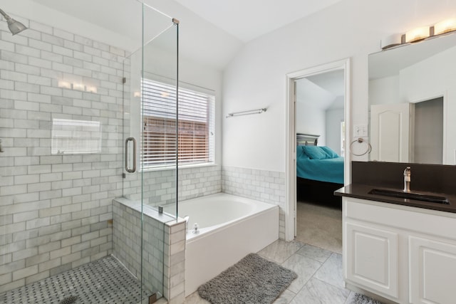 bathroom featuring a shower stall, lofted ceiling, vanity, a bath, and ensuite bath