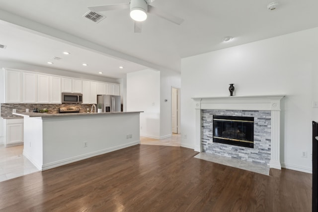 unfurnished living room with light wood-style flooring, visible vents, and ceiling fan