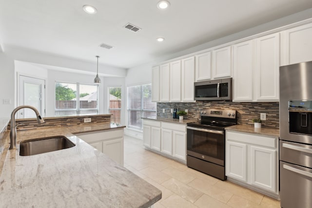 kitchen with white cabinets, recessed lighting, backsplash, a sink, and appliances with stainless steel finishes