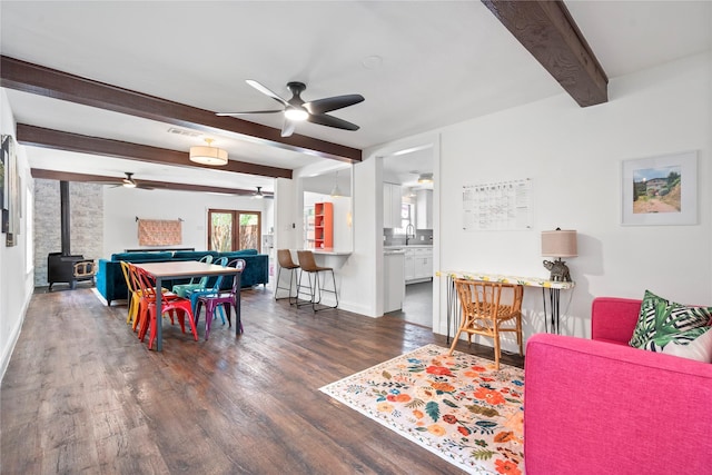 2744 Bay Meadows Ct, Farmers Branch, TX 75234 - dining space with ceiling fan, beamed ceiling, healthy amount of natural light, dark wood-style flooring, and a wood stove
