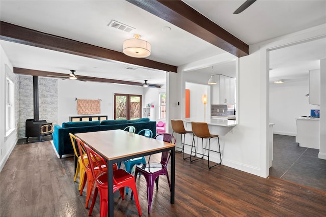 2744 Bay Meadows Ct, Farmers Branch, TX 75234 - dining room with ceiling fan, a wood stove, beam ceiling, dark wood finished floors, and baseboards