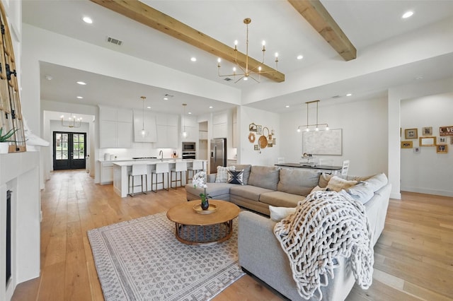living area with light wood finished floors, a chandelier, recessed lighting, beamed ceiling, and visible vents