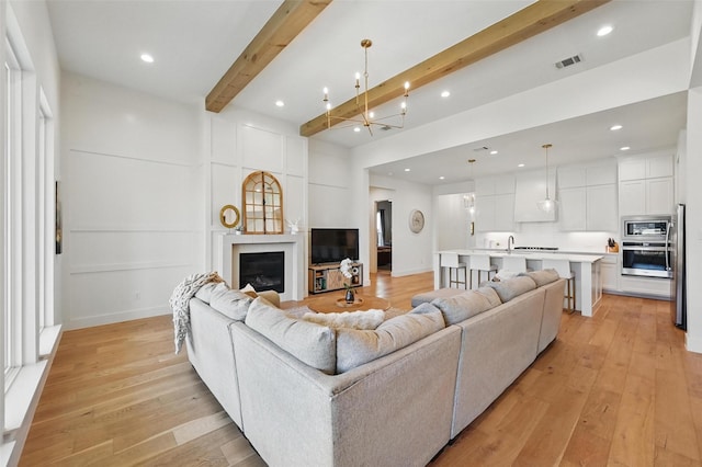 1109 Mountain View Dr, Weatherford, TX 76087 - kitchen with a sink, white cabinets, a notable chandelier, stainless steel appliances, and light wood-style flooring