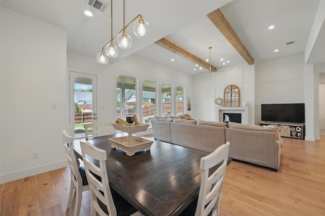 dining area featuring visible vents, a fireplace, beamed ceiling, light wood-style floors, and baseboards
