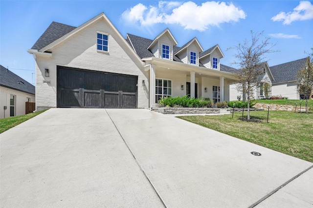 view of front of property with a porch, driveway, a garage, a front lawn, and a shingled roof