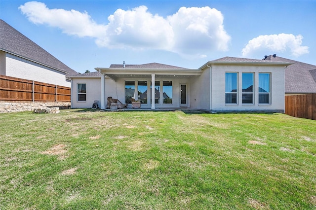 rear view of property featuring a lawn, brick siding, and a fenced backyard