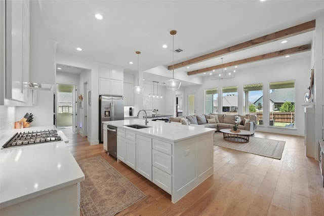 kitchen featuring beamed ceiling, light countertops, white cabinets, a sink, and light wood finished floors