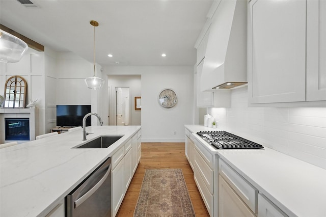 kitchen with appliances with stainless steel finishes, tasteful backsplash, a sink, custom exhaust hood, and recessed lighting