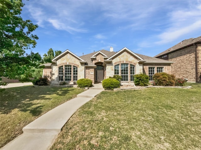 single story home featuring roof with shingles, stone siding, and a front yard