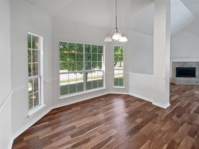 unfurnished dining area with high vaulted ceiling, wood finished floors, a chandelier, a fireplace, and baseboards