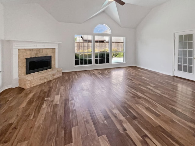 unfurnished living room with lofted ceiling, wood finished floors, a ceiling fan, and a stone fireplace