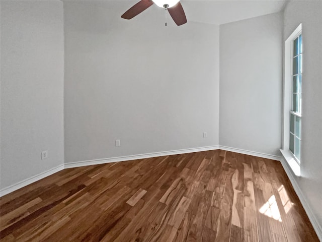 unfurnished room featuring baseboards, dark wood-style floors, and ceiling fan