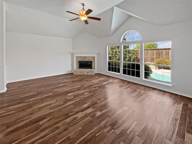 unfurnished living room with vaulted ceiling, wood finished floors, baseboards, a glass covered fireplace, and ceiling fan