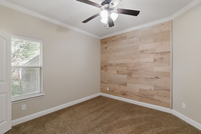 carpeted spare room with plenty of natural light, a ceiling fan, ornamental molding, and wood walls