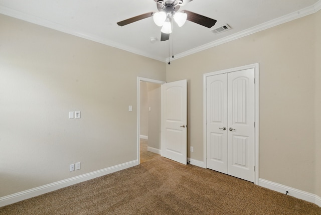 unfurnished bedroom with crown molding, a closet, carpet, baseboards, and visible vents