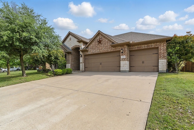 french provincial home featuring concrete driveway, brick siding, a front yard, and a garage