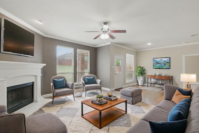 living room with ceiling fan, baseboards, crown molding, and a fireplace