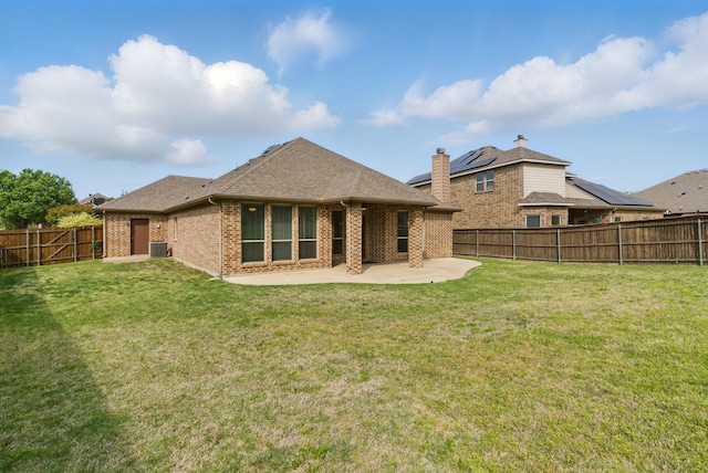 rear view of house with brick siding, a patio area, a lawn, and a fenced backyard