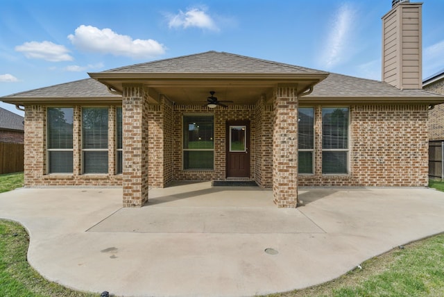 property entrance with ceiling fan, brick siding, roof with shingles, and a patio