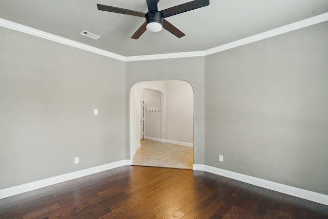 empty room with hardwood / wood-style flooring, ceiling fan, arched walkways, and crown molding