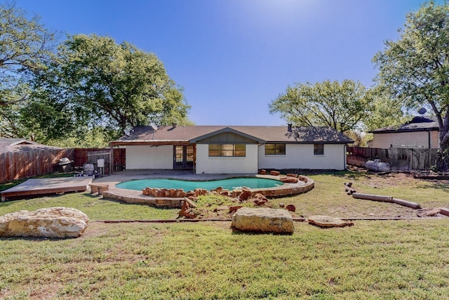 rear view of house with a lawn, a fenced backyard, a fenced in pool, and french doors