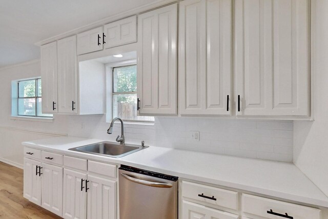 kitchen featuring dishwasher, a sink, white cabinetry, and tasteful backsplash
