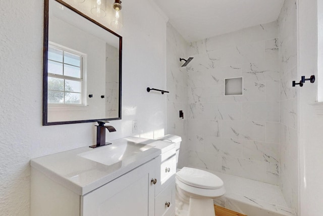 bathroom with toilet, vanity, and a tile shower