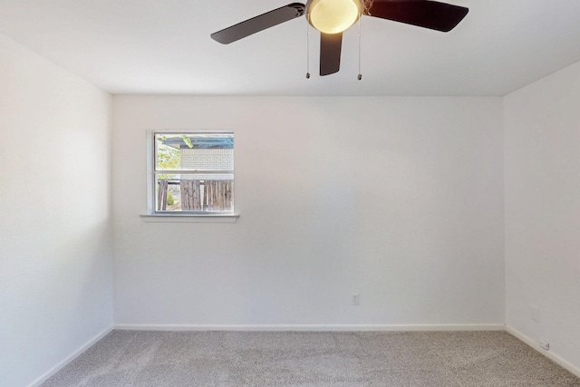 carpeted empty room with a ceiling fan and baseboards