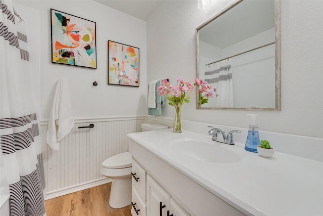 bathroom featuring wood finished floors, wainscoting, vanity, a shower with curtain, and toilet