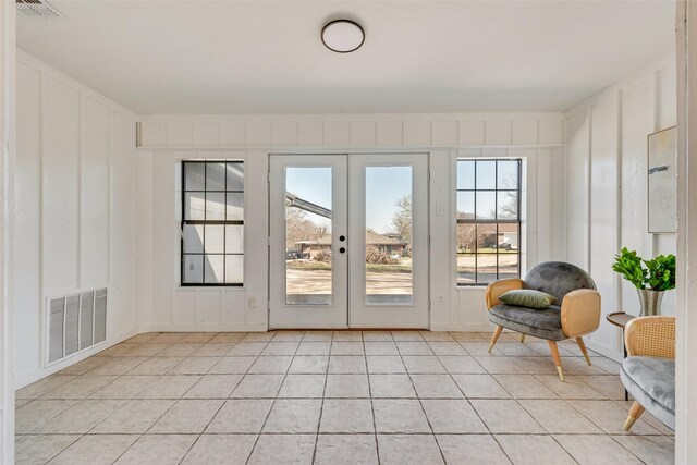 entryway with a decorative wall, french doors, visible vents, and light tile patterned floors