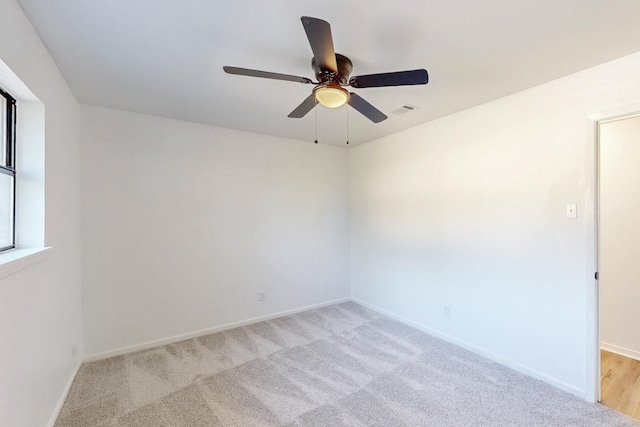 unfurnished room featuring visible vents, a ceiling fan, baseboards, and light carpet