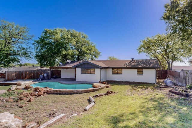 back of property with a fenced backyard, a fenced in pool, and a lawn