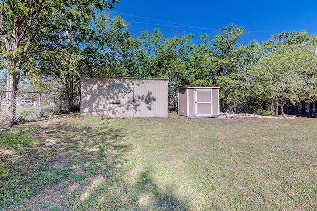 view of yard with fence, a storage unit, and an outbuilding