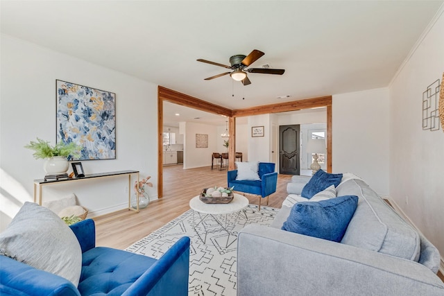 living room with ornamental molding, baseboards, light wood-style floors, and ceiling fan