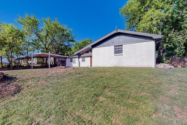 exterior space with fence, a lawn, brick siding, and a detached carport