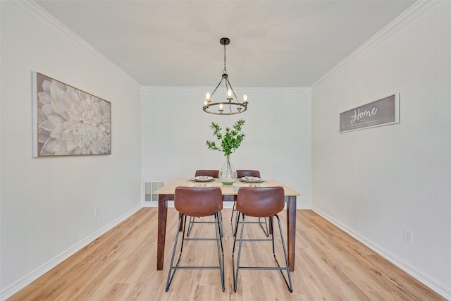 dining room with a chandelier, light wood-style floors, and crown molding