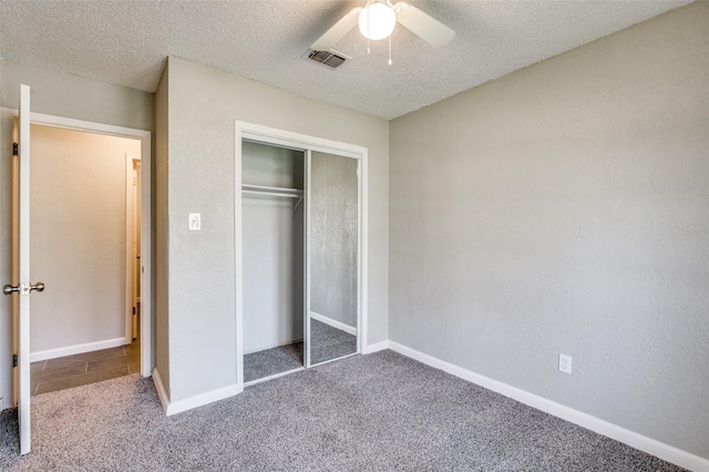 unfurnished bedroom featuring visible vents, carpet, a textured ceiling, and a closet