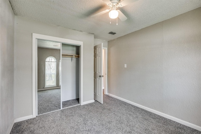 unfurnished bedroom featuring carpet floors, a textured ceiling, visible vents, and a closet