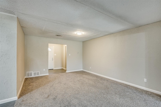 unfurnished room with visible vents, carpet, and a textured ceiling