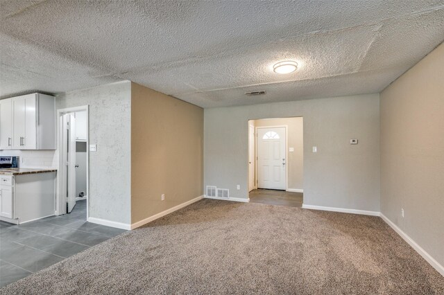 interior space featuring dark colored carpet, visible vents, and baseboards