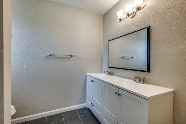 bathroom featuring tile patterned floors, a sink, a textured ceiling, and double vanity