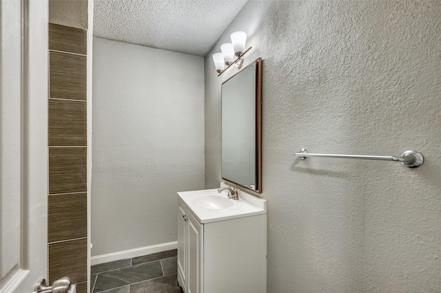 bathroom with tile patterned floors, baseboards, vanity, and a textured ceiling