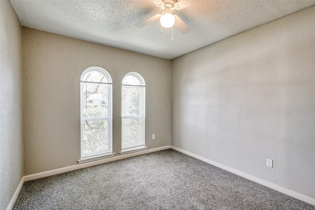 carpeted empty room with baseboards, a ceiling fan, and a textured ceiling