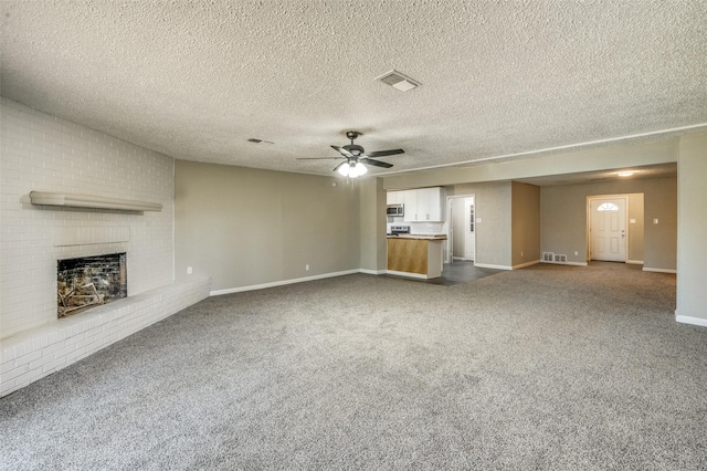 unfurnished living room with dark carpet, baseboards, a brick fireplace, and visible vents